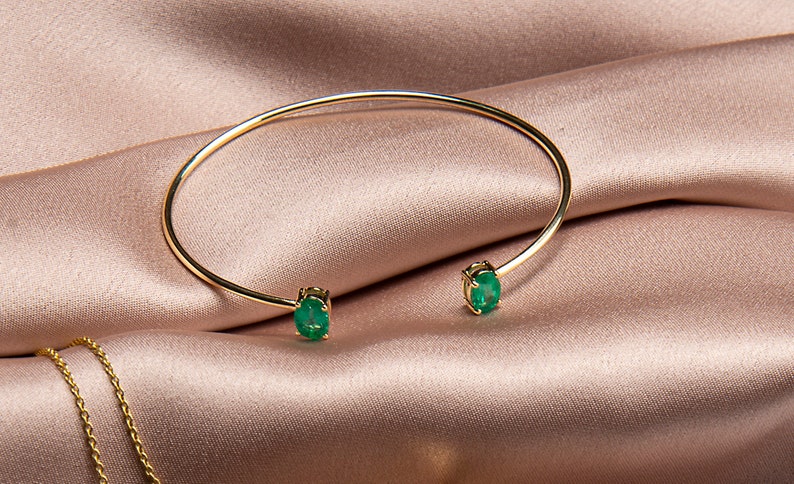 14k yellow gold bangle set with a matching pair oval Cut emerald