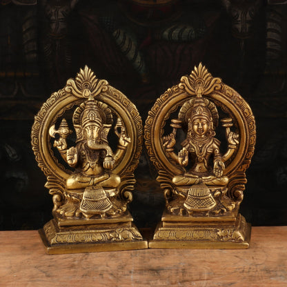 Pair of ornate brass statues on a wooden surface with a dark background