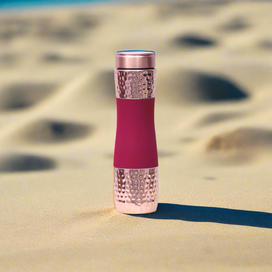 Pink and rose gold textured bottle on sand