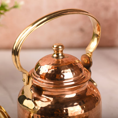 Copper kettle with gold handle on a light background