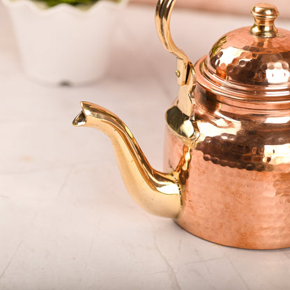 Copper teapot with gold accents on a light background