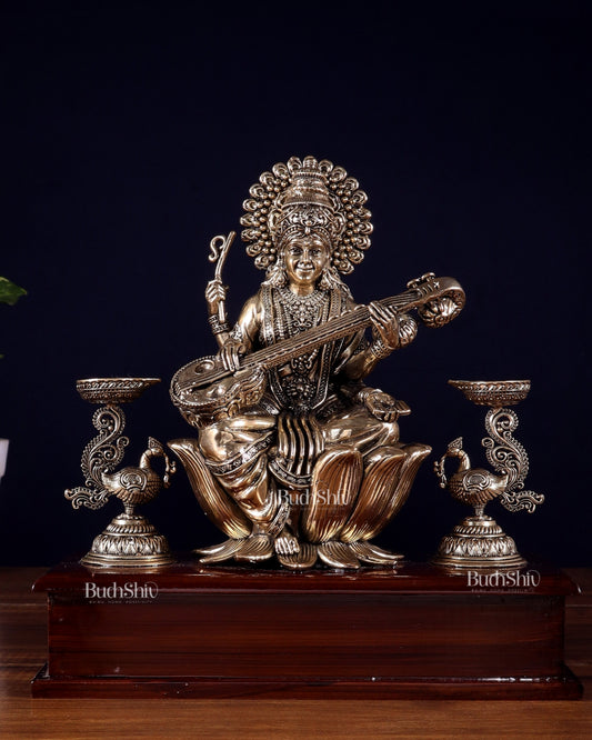Brass Superfine Goddess Saraswati Idol with Twin Peacock Lamps on Wooden Base – 9.5 Inch - Sama Homes Idol - Brass Sculpture