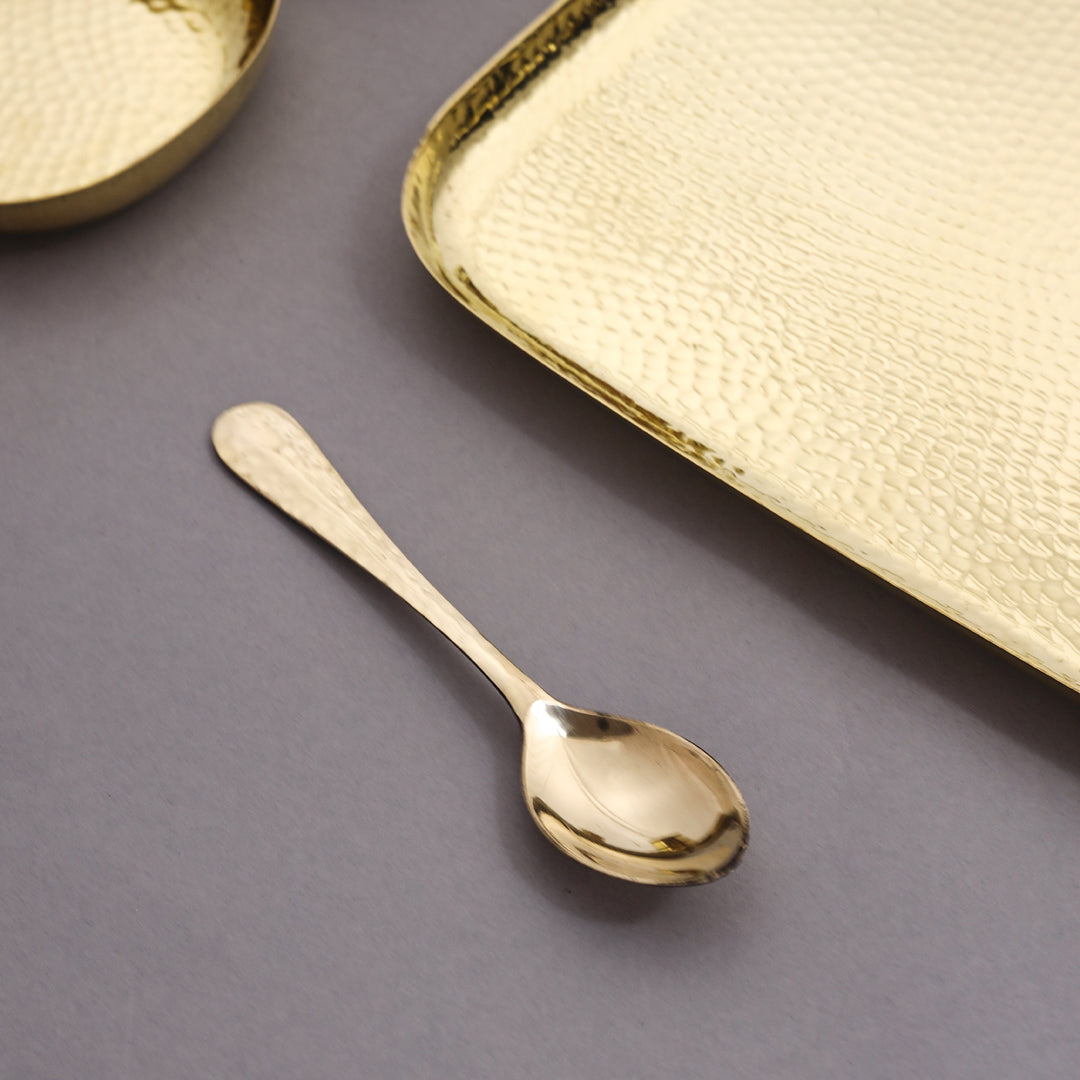 Gold spoon and tray on a gray surface