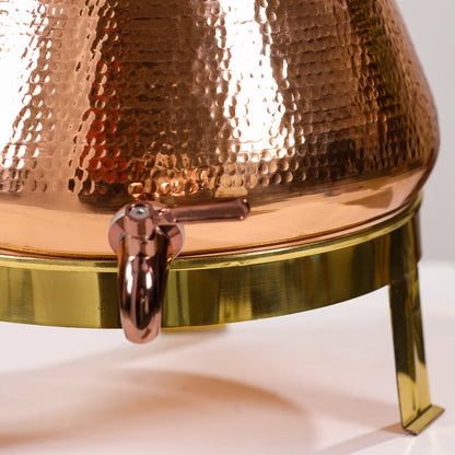 Close-up of a copper and brass container with a spout on a white background
