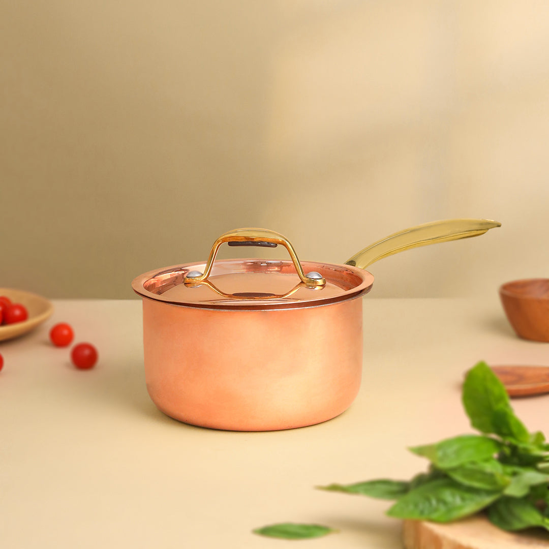 Copper pot with a lid on a light surface with greenery and small items. - Image 2