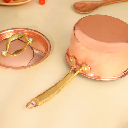 Copper saucepan with gold handle on a beige background