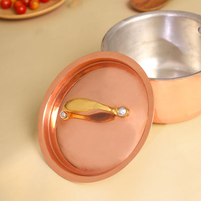 Copper pot lid with a gold handle on a beige surface