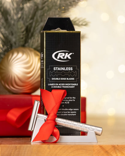 RK stainless double edge blades packaging with a silver razor and red ribbon on a blurred festive background