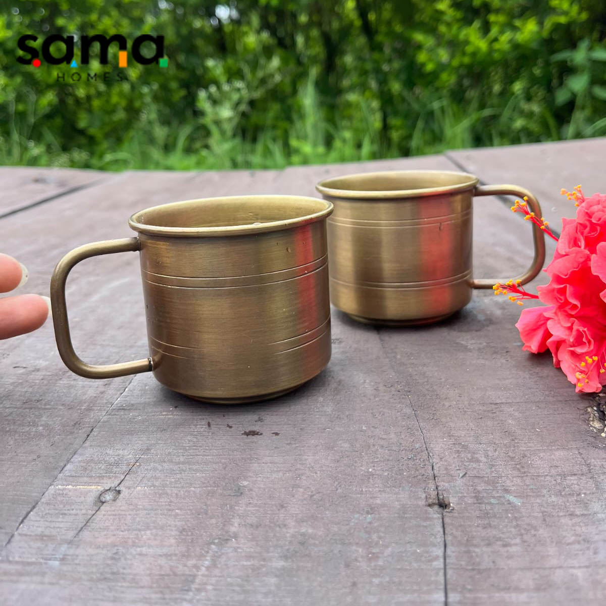 A brass antique coffee mug with a handle, placed on a wooden surface next to a pink flower, with the brand 'Sama' visible in the corner. - Image 2